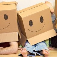 Smiley moving family concept - couple with a kid and lots of cardboard boxes